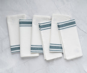 Four bistro napkins in white with blue stripes neatly arranged