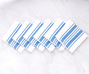 Six blue and white striped restaurant napkins displayed on a marble surface