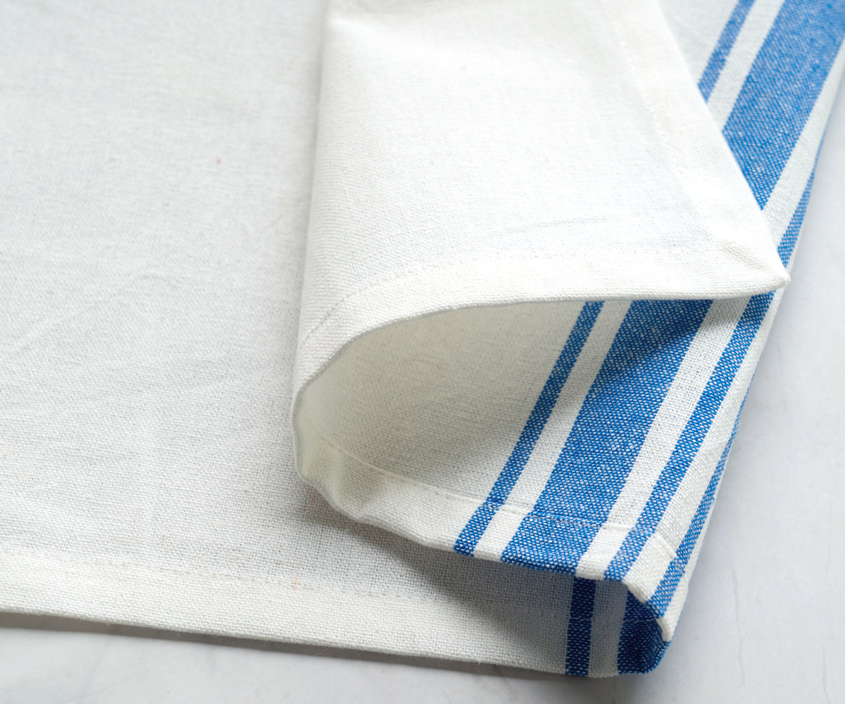 A set of six bistro napkins with blue and white stripes displayed on a table