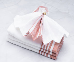 Four stacked linen dinner napkins in white and pink