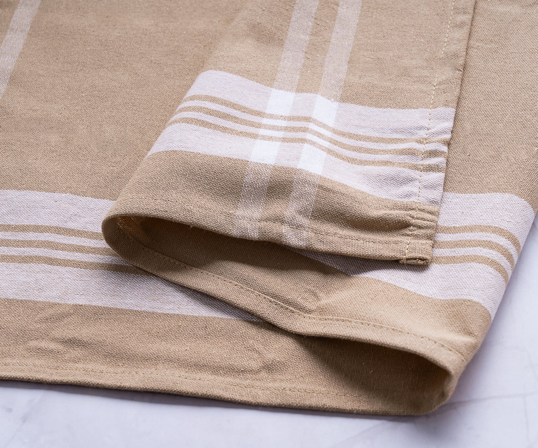 Detailed view of a beige farmhouse kitchen towel with white and tan stripes