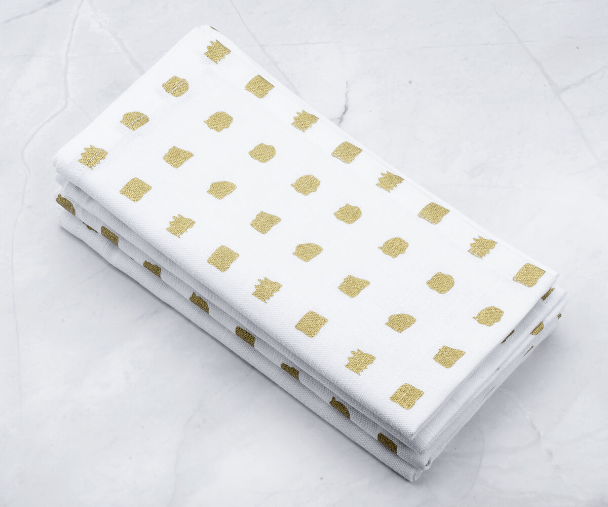 Set of 4 folded Printed cocktail napkins-gold dinner napkins are arranged one above another.