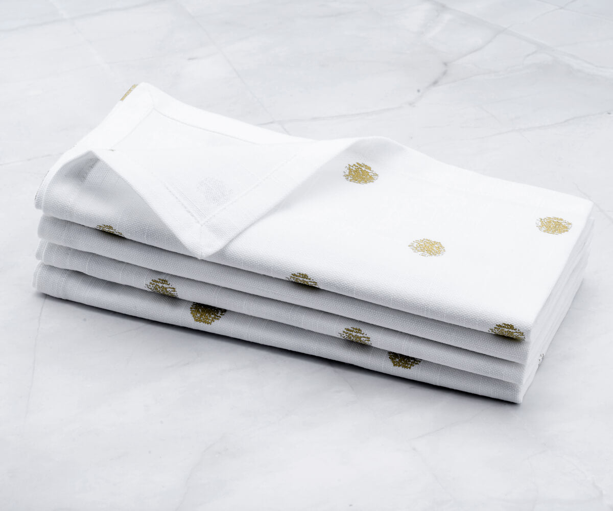 Folded set of 4 White Cloth napkins-White and gold napkins are arranged one above another.
