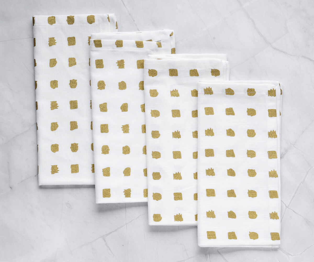 Set of 4 Folded Metallic - gold napkins -printed wedding napkins  are arranged one above another.