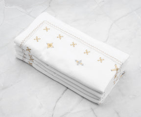 White dinner napkins folded into a pyramid shape, placed beside polished silverware on a formal dining table.