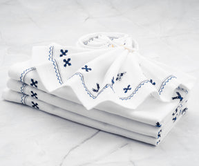 Elegant white dinner napkins neatly folded on a dinner table set with fine china and crystal glassware.