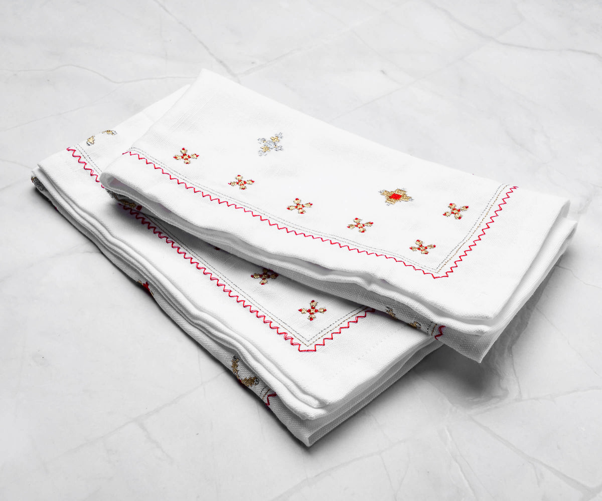 Red dinner napkins folded into a pyramid shape, placed beside polished silverware on a formal dining table.