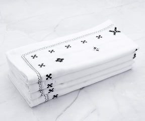 Stack of crisp white dinner napkins with a subtle embroidered border, perfect for formal dining.
