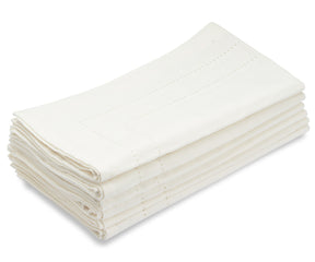 Collection of white double hemstitch cloth napkins stacked on a white table