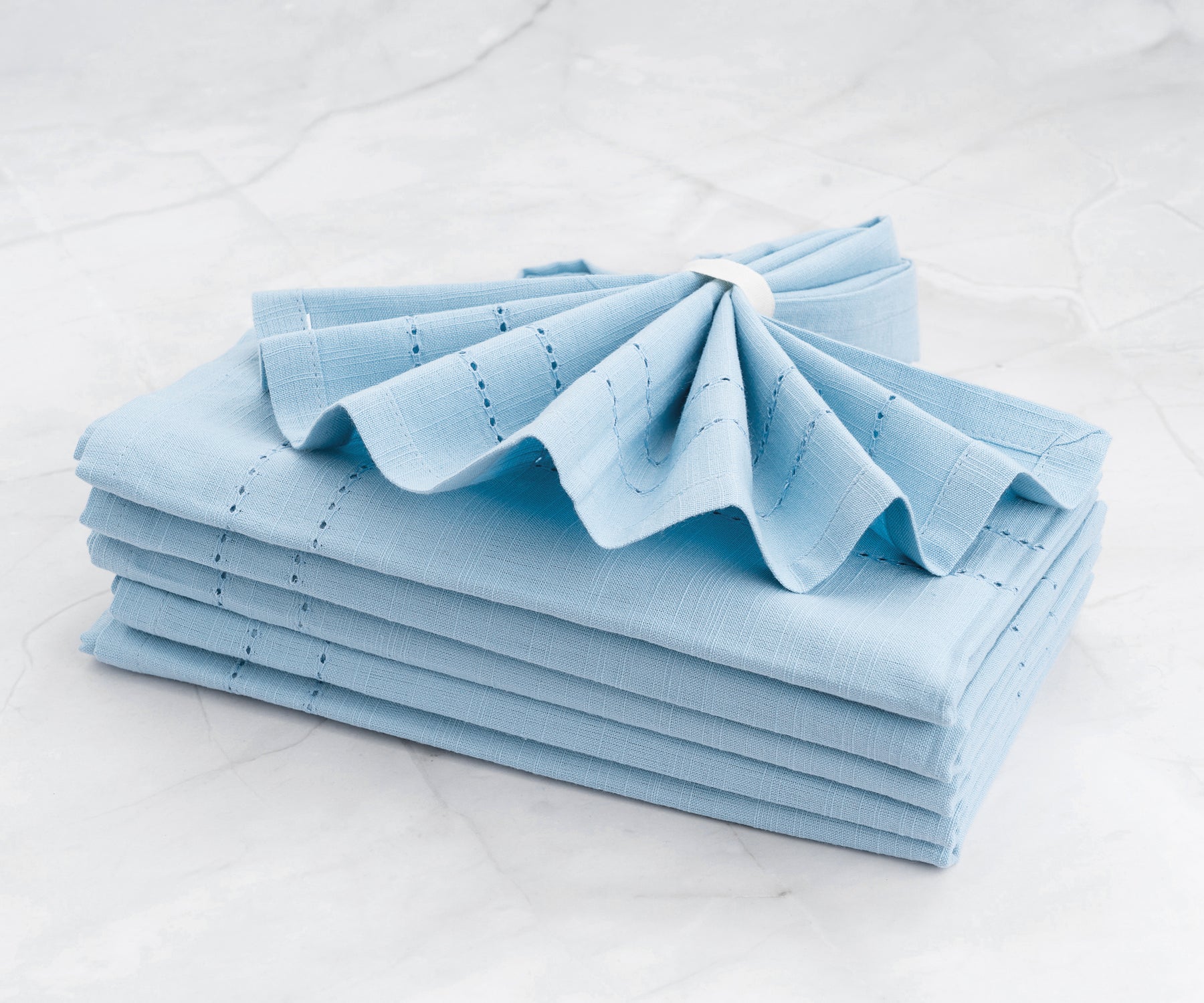 Neatly stacked Cloth Dinner Napkins in blue on a polished marble countertop