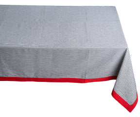 Farmhouse tablecloth with red border and grey and white stripes on a table