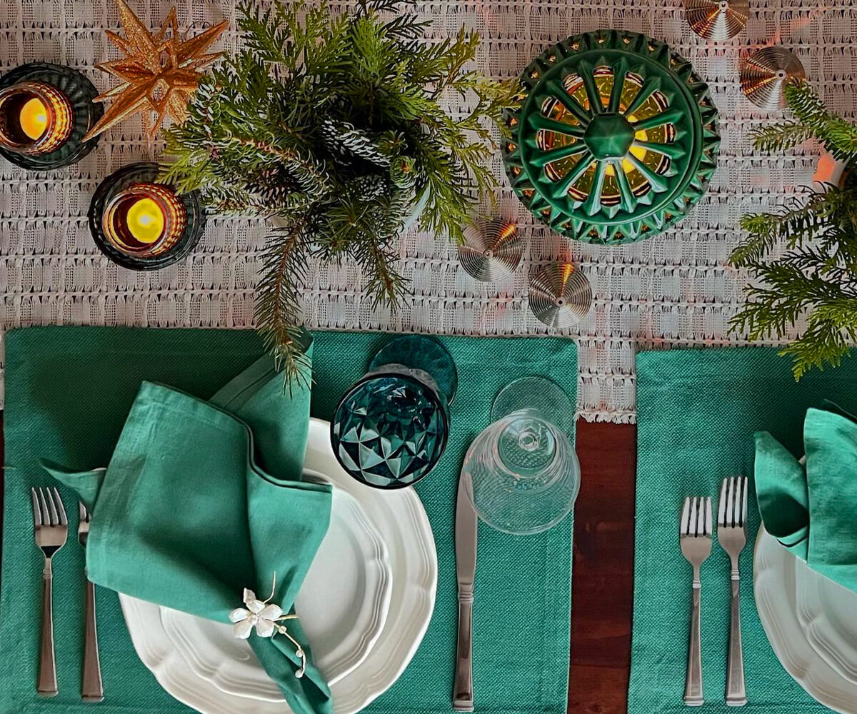 The green-colored linen napkins with 1" borders are arranged on the dining table napkins with spoons