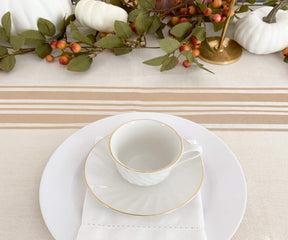 Table adorned with round outdoor tablecloth, gold and white plates, and a gold cup