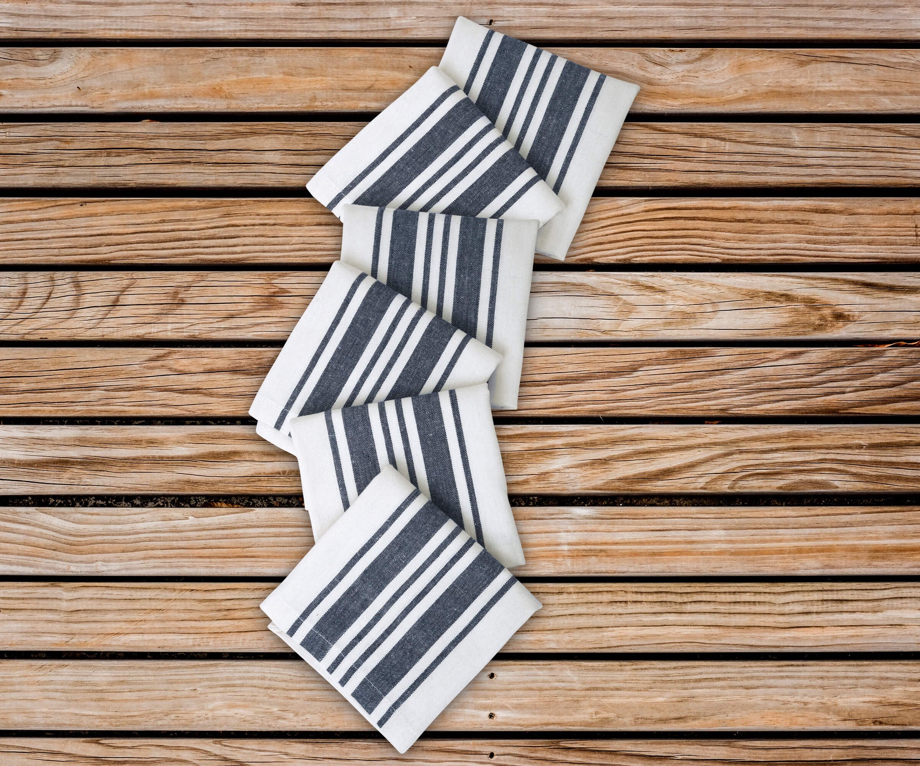 Cotton napkins as blue napkins cloth - Bistro Napkins with blue stripe features navy blue cloth napkins are arranged in the zig zag pattern on the table.