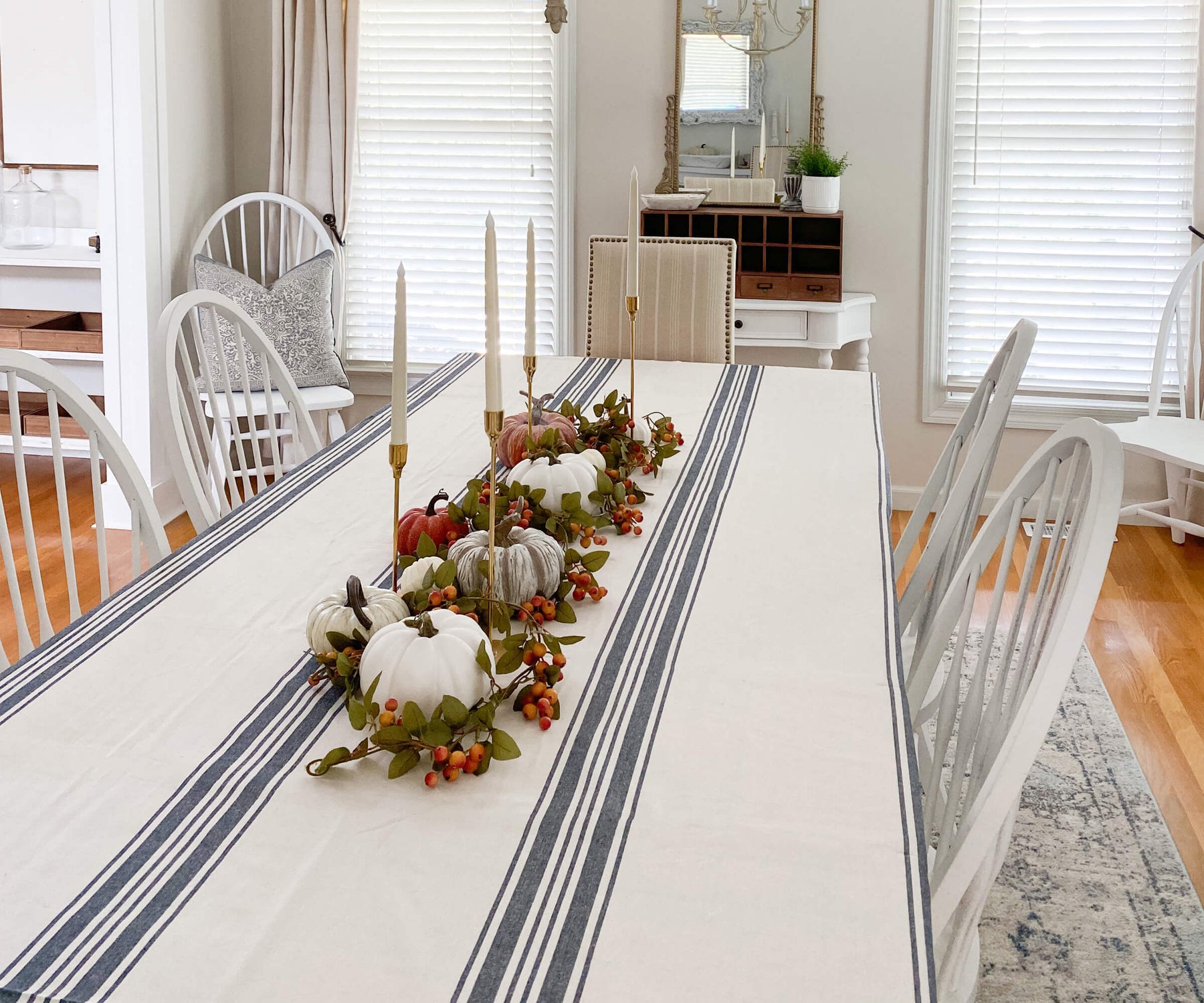 Dining table with white chairs and a striped Farmhouse tablecloth
