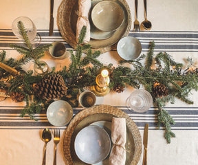 Christmas table setting featuring a farmhouse tablecloth, plates, and silverware