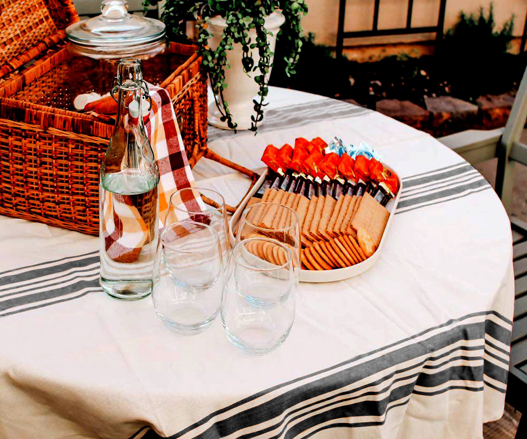 Round outdoor tablecloth on a table with a picnic setup of food and wine