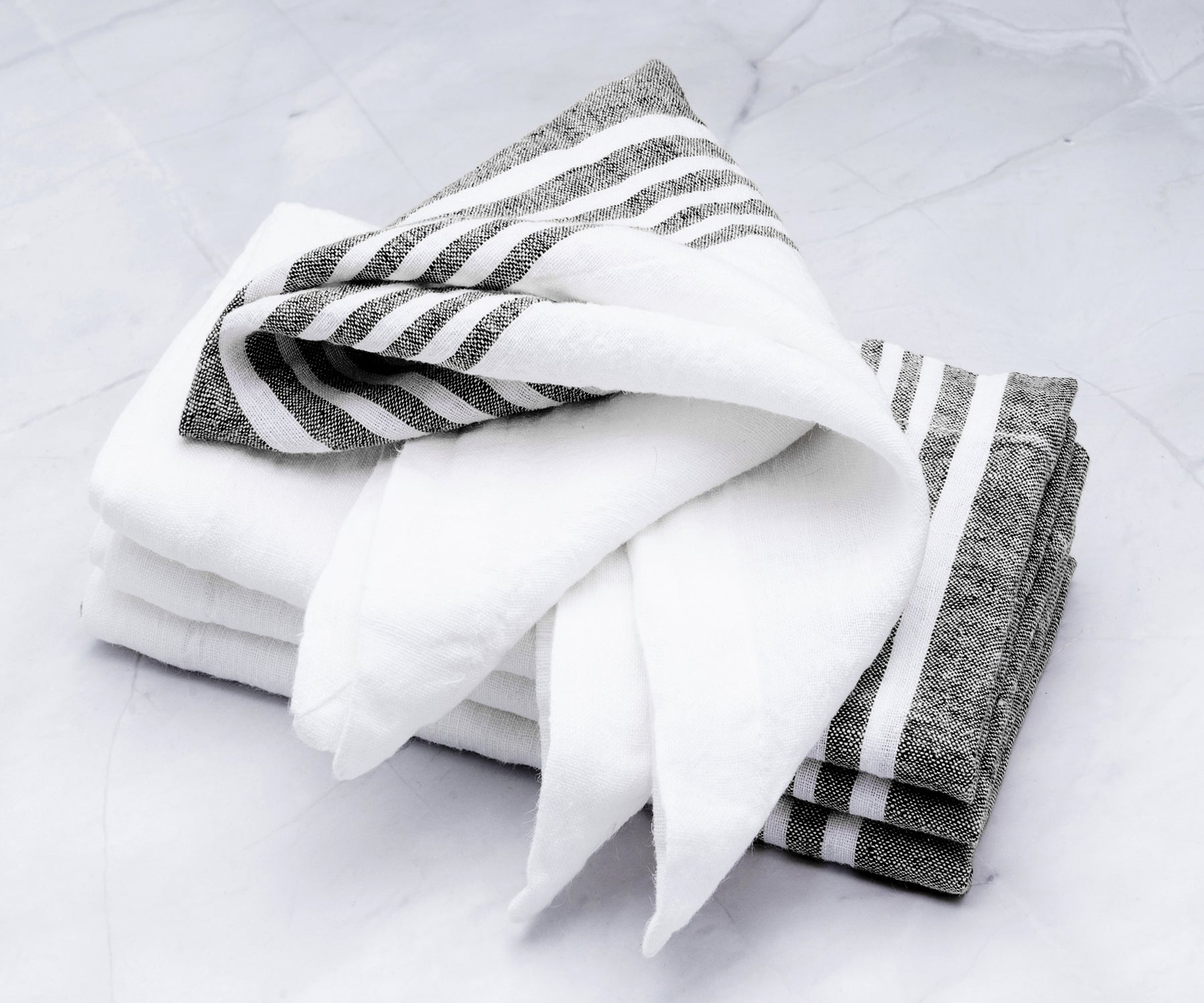 Stack of linen dinner napkins featuring white and gray stripes