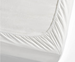 Detailed view of a mattress covered with a white cotton fitted sheet