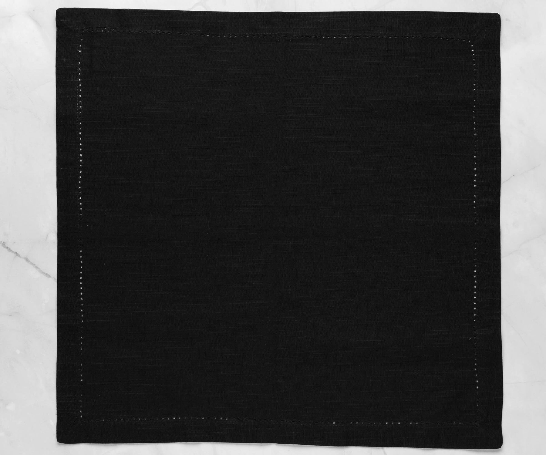 Hemstitched dark black tea party napkins with 1-inch border on the white floor