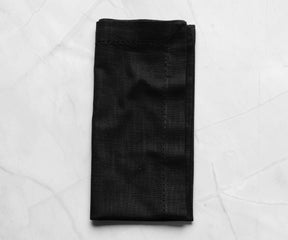 Folded Hemstitched black cloth napkins ,tea party napkins with 1" borders are placed on the white floor.