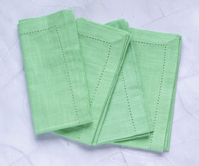 green cloth napkins with 1" borders are arranged alternately on the floor, sage green napkins are used as easter napkins