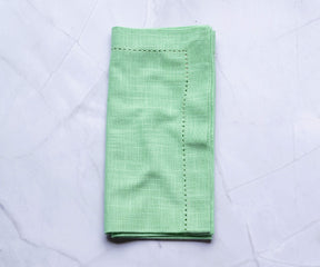 Eton green-colored cloth napkins, easter dinner napkins with borders are folded and placed on the white floor.