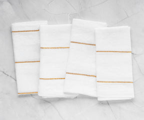 Transform your table settings with a selection of dinner napkins, encompassing cloth and folding variations, in white and black alternatives.Detailed Shot of Gold Linen Napkins with a Charming Texture