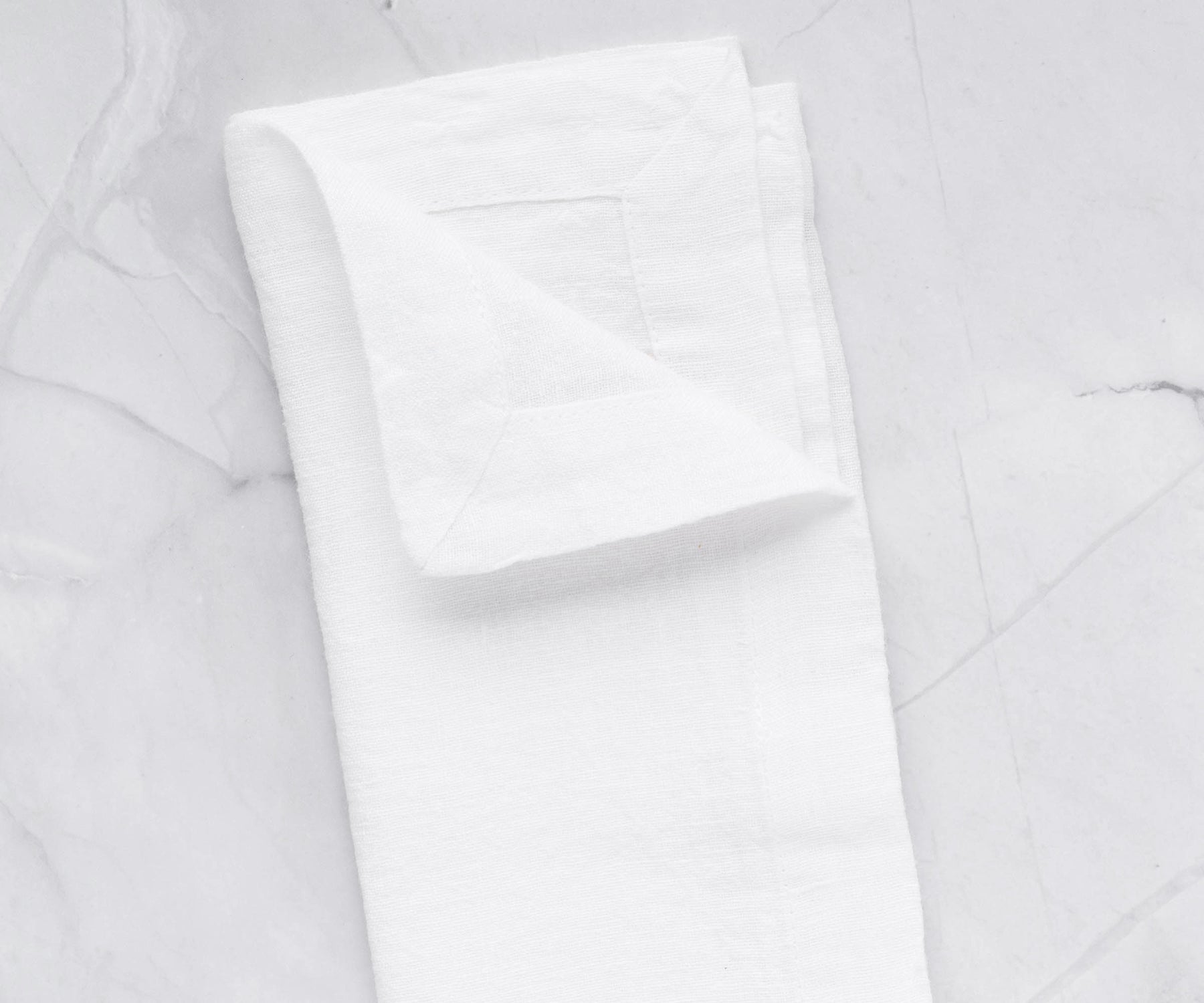 Folded white linen napkin on a marble tabletop