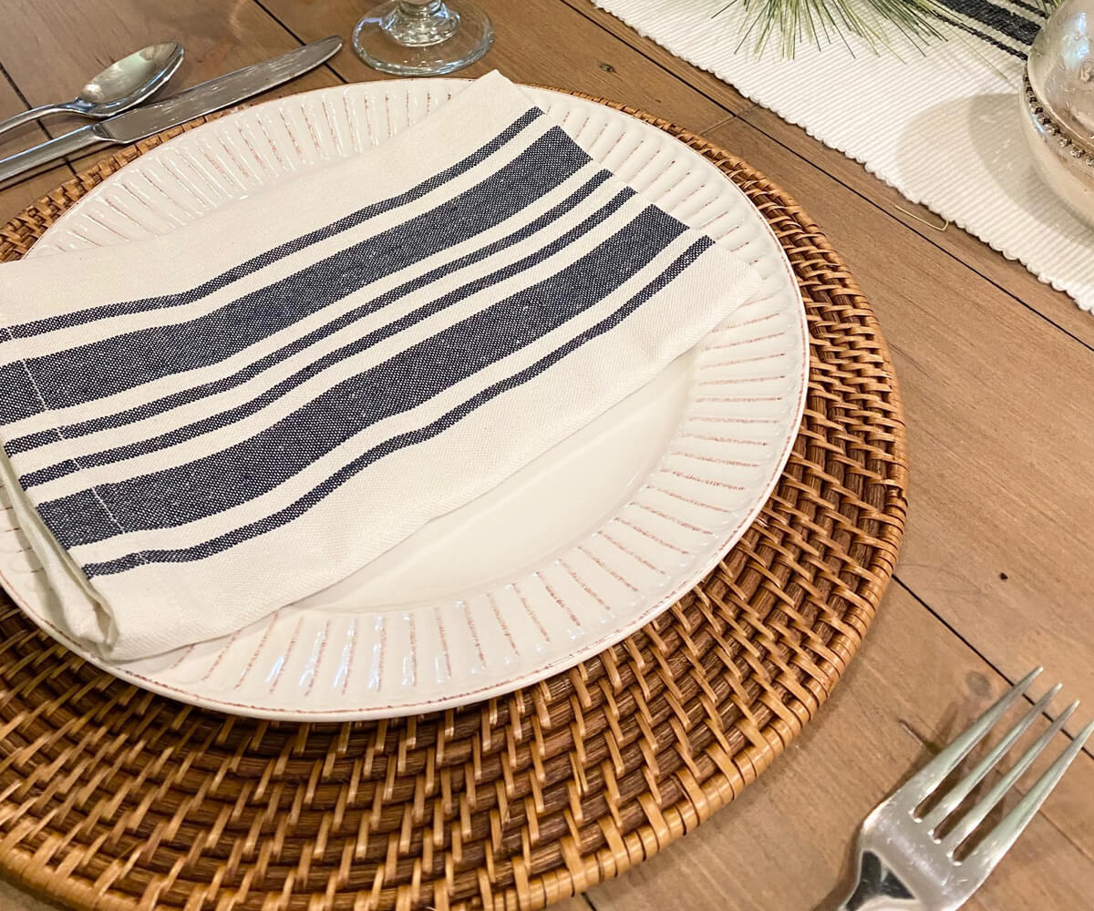 White cloth napkins - Folded dinner napkins which are striped napkins features navy blue cloth napkins with  are placed on the placemats with spoons and fork.