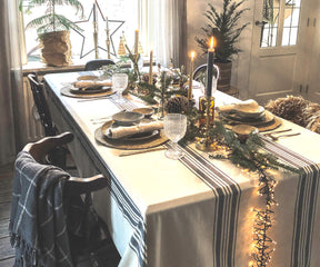 Christmas dinner table set up featuring a farmhouse tablecloth and candles