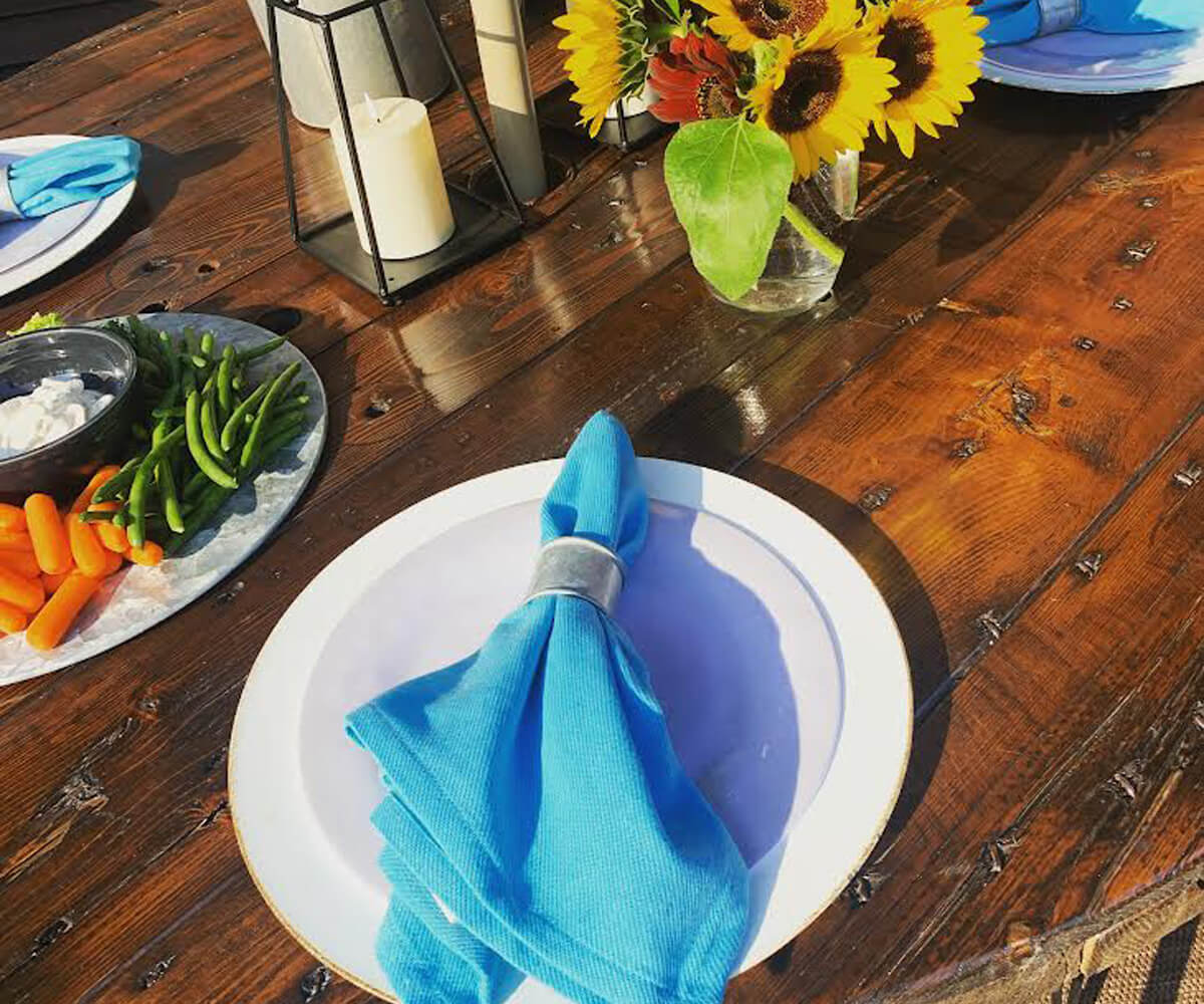 The Aqua colored cotton dinner cloth napkins with 1" borders with napkin rings are placed on the plate