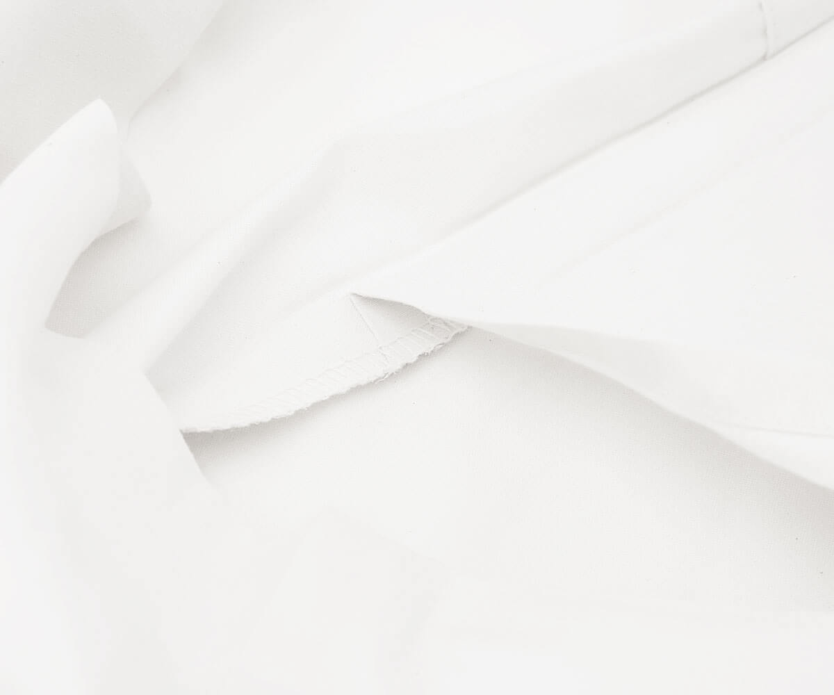 Close up view of a folded white cotton fitted sheet